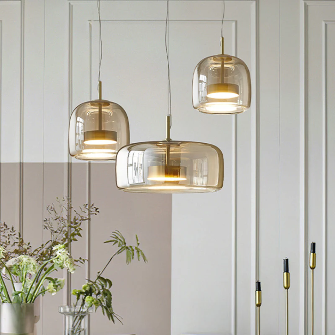 Ensemble de trois luminaires Éclat combinant des finitions en verre ambré et transparent pour un effet luxueux.