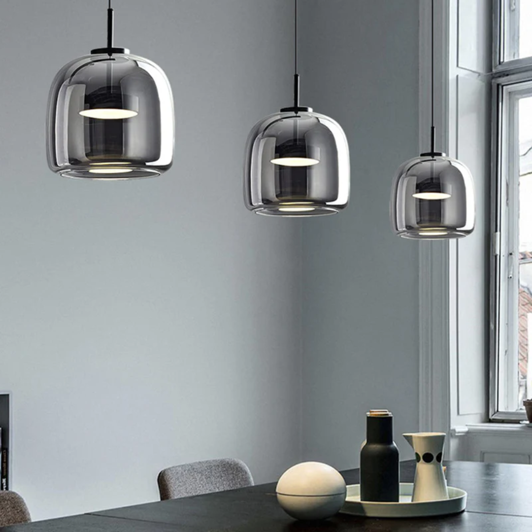 Alignement de trois suspensions Éclat en verre fumé gris au-dessus d'une table dans un intérieur contemporain.
