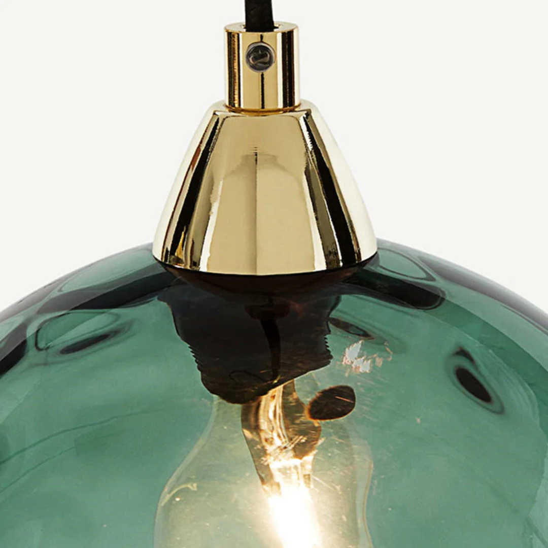 Détail d'une douille en métal doré fixée sur un globe en verre strié de couleur vert émeraude.