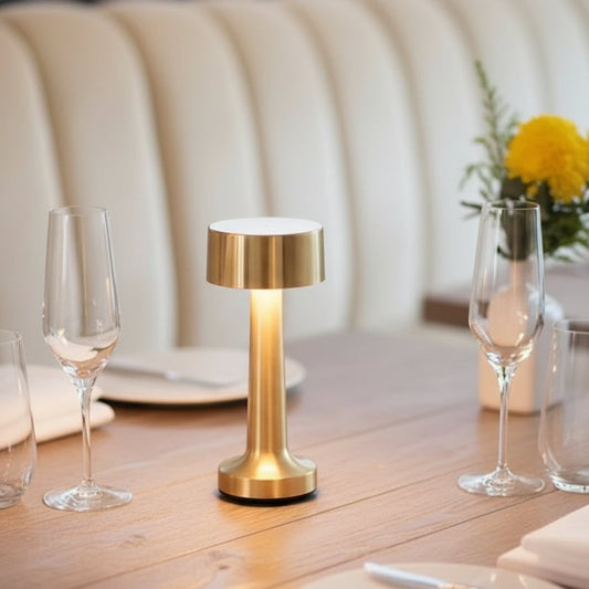 Lampe de table rechargeable Epure dorée sur une table de restaurant de luxe.