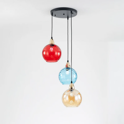 Lustre triple avec base ronde noire et globes en verre strié rouge, bleu et ambre.