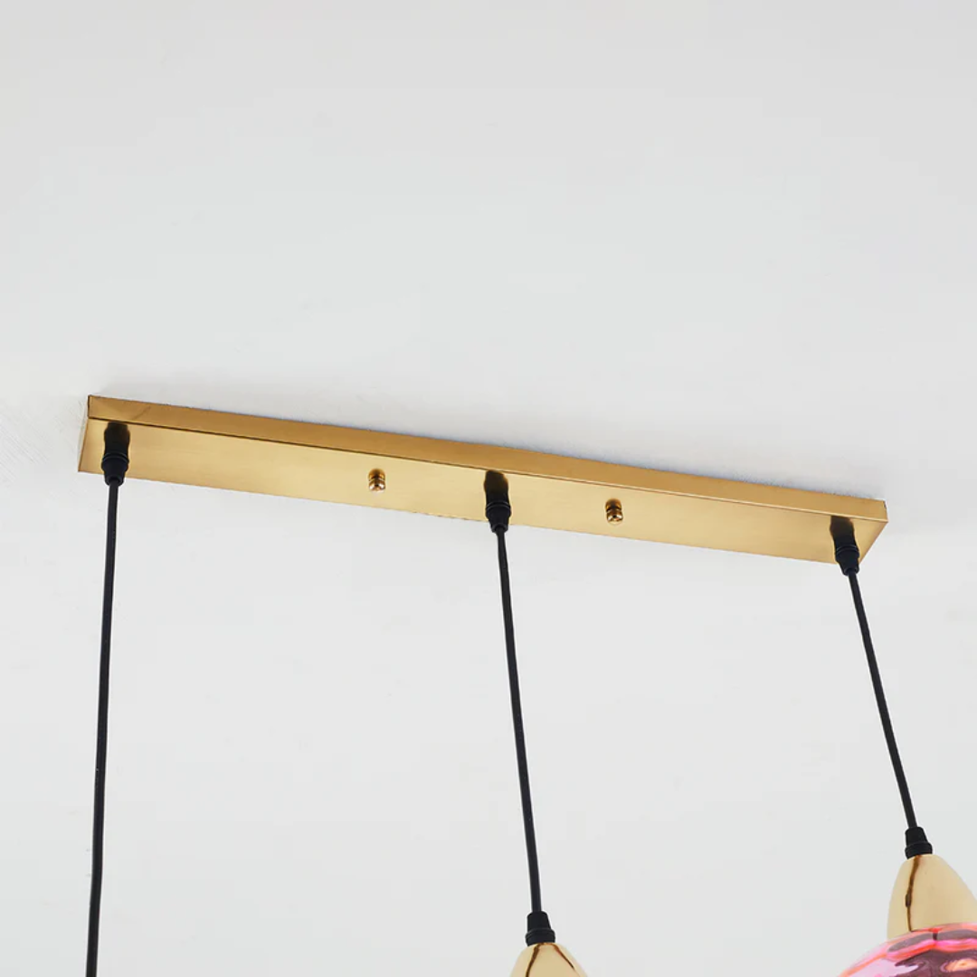 Détail de la barre de fixation horizontale dorée pour lustre triple avec câbles réglables.