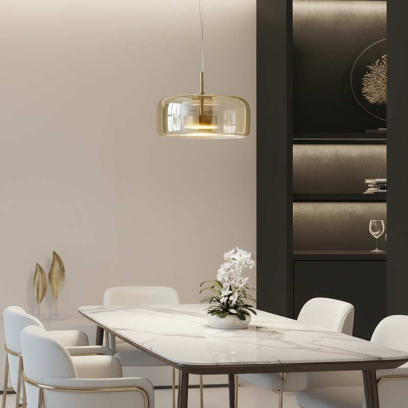 Suspension design Éclat en verre ambré installée au-dessus d'une grande table de salle à manger en marbre.