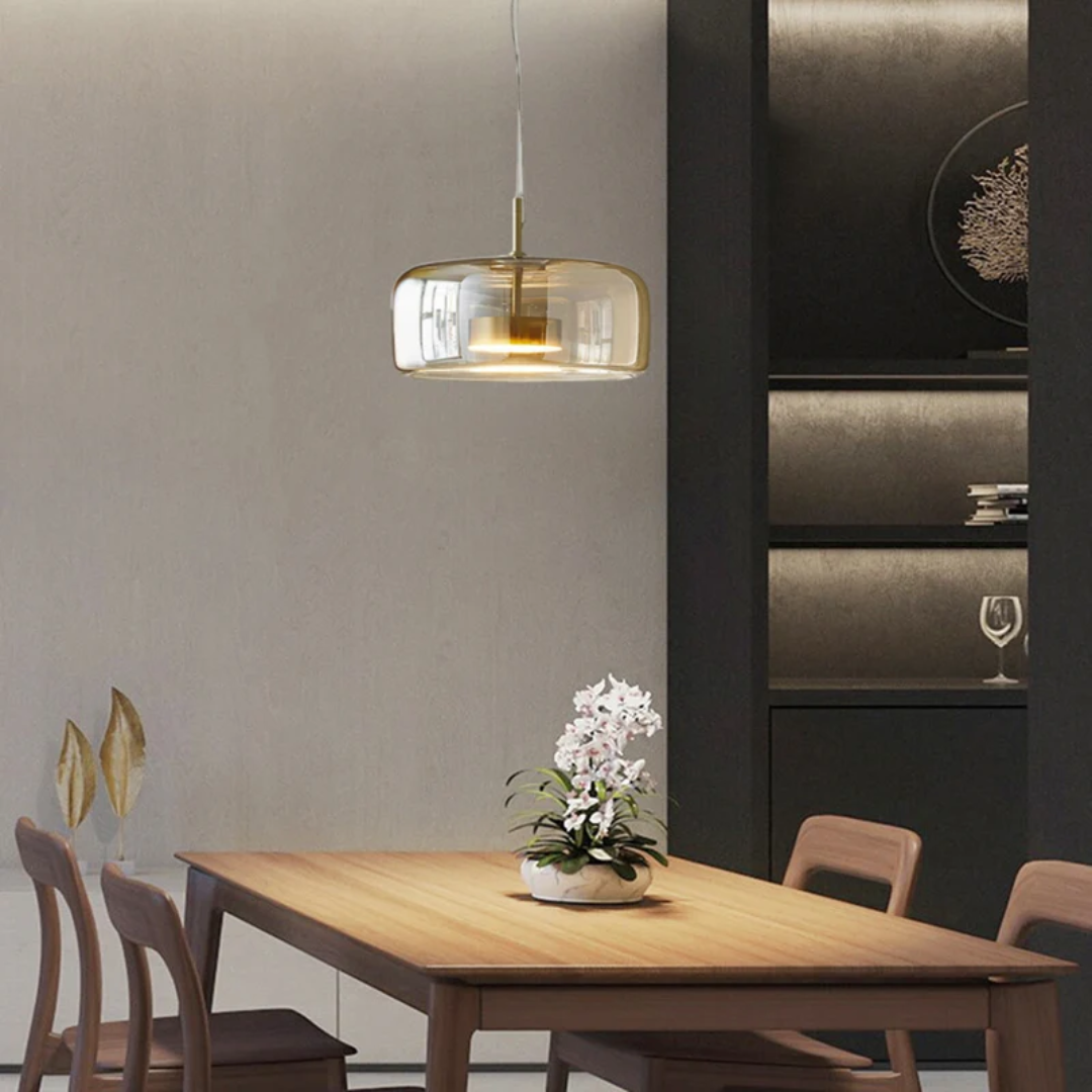 Lampe suspendue Éclat ambrée diffusant une lumière chaude au-dessus d'une table de salle à manger en bois.